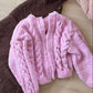 Pink and brown knitted sweaters on a light wooden floor